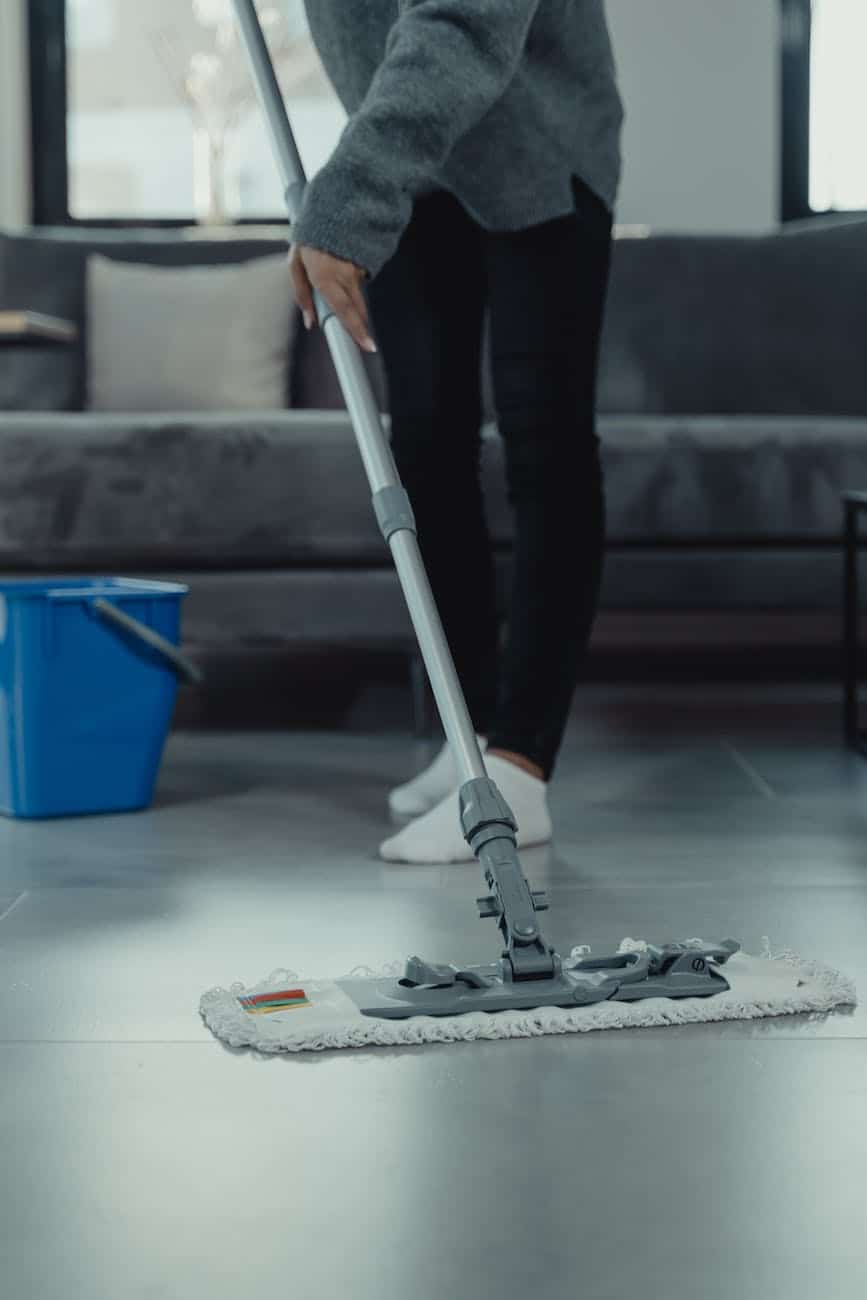 person in gray sweater mopping and cleaning the floor